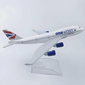 以下が含まれることがあります： 青いエンジンと「one world」と「British Airways」の文字が入った白い模型飛行機。尾翼には赤、白、青のデザインが施されています。透明なスタンドに飾られています。