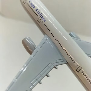 May include: A white and gray model airplane with the text "Copa Airlines" printed on the side. The airplane has gray wings and a gray engine. The model is angled, showing the top and side.
