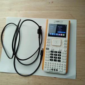 May include: A white and orange graphing calculator with a black cable. The calculator has a screen that displays "TI-Nspire CX II" and "Texas Instruments". The screen also shows a menu with options for "Spreadsheet", "Calculate", "Graph", "Documents", "New", "Browse", "MyDocs", "Current", and "Settings". The calculator has a keypad with numbers, letters, and symbols. The calculator also has a touchpad and a button that says "SCHOOL PROPERTY".