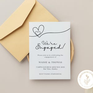 Puede incluir: Una tarjeta de anuncio de compromiso blanca con un dibujo de línea negra de dos corazones entrelazados. El texto dice "We're Engaged!" e incluye los nombres de la pareja, la fecha, la hora y el lugar de la celebración. También se incluye la información de RSVP.