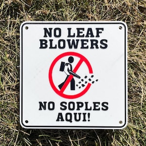 Peut inclure: Panneau carré blanc avec texte noir « NO LEAF BLOWERS » et « NO SOPLES AQUI ! ». Un cercle rouge barré contient une silhouette noire d'une personne utilisant un souffleur de feuilles. Le panneau est posé sur un lit d'herbe.