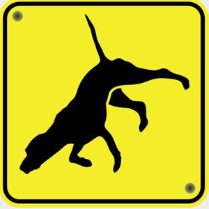 May include: A yellow square sign with a black border and a black silhouette of a dog in mid-leap. The sign has two silver rivets in the corners.
