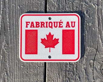 May include: White sign with red text and a red maple leaf. The sign reads "Fabriqué au".