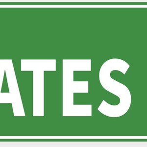 Pode incluir: Uma placa de rua verde com texto branco que diz "YATES DR". A placa tem uma borda branca e é montada com dois rebites prateados. A placa é retangular.