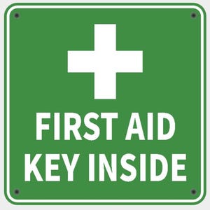 May include: A square, green sign featuring a white cross at the top. The text "FIRST AID KEY INSIDE" is displayed in white, beneath the cross. The sign has a white border and is fixed with four small rivets, indicating first aid provision.