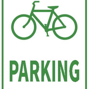 以下が含まれることがあります： 緑色の自転車のグラフィックが上部に描かれた、緑色の縁取りのある長方形の白い標識。「PARKING」の文字が自転車の下に大きな緑色の文字で印刷されています。標識には4つの小さな灰色のリベットが付いています。