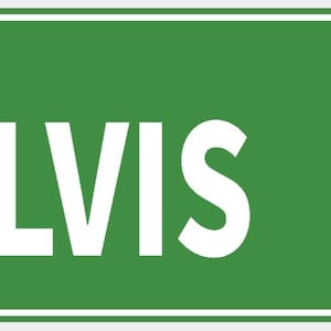 Pode incluir: Uma placa de rua retangular verde com texto branco que diz "ALVIS DR". A placa tem uma borda branca e é montada com dois rebites. As letras são em negrito e fáceis de ler.