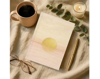 Peut inclure: Un carnet avec un motif de soleil doré, un stylo doré, une tasse de café, une bougie allumée et des lunettes sur une surface beige. Le carnet a un motif de style aquarelle avec un soleil doré et une ligne dorée.