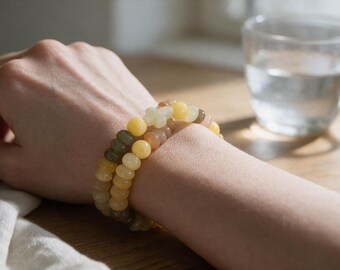 Rosario pulsera en cuentas planas de colores claros.