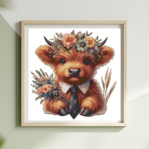 May include: A framed watercolor print of a Highland cow calf. The calf has brown fur, a floral crown, and a black tie. It holds a bouquet of flowers. The artwork is in a light wooden frame.