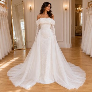 Elegante vestido de novia color marfil con corte sirena y hombros descubiertos: perlas y encaje.