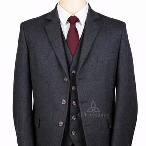 Puede incluir: Un traje de tres piezas gris carbón con chaqueta, chaleco y pantalón a juego. El traje incluye una camisa blanca y una corbata burdeos. El logotipo de Celtic Costume es visible.