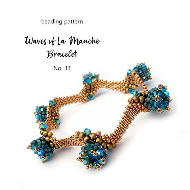 K&ouml;nnte beinhalten: Ein goldfarbenes Perlenarmband mit t&uuml;rkisfarbenen und blauen Perlenclustern. Das Armband tr&auml;gt die Aufschrift "Waves of La Manche Bracelet" und "No. 33". Das Design weist ein gewebtes Muster auf.