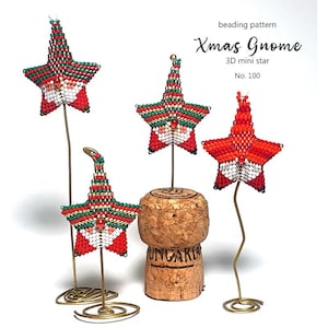 Puede incluir: Cuatro adornos de estrellas de cuentas en rojo, verde y blanco, con soportes de alambre dorado. Una estrella está montada en un corcho. El texto dice "Xmas Gnome 3D mini star No. 100" y "beading pattern".