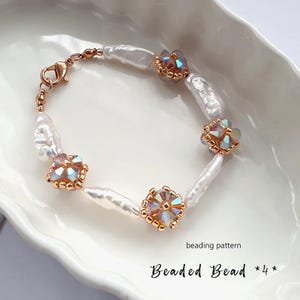 Könnte beinhalten: Zartes Armband mit weißen Barockperlen und irisierenden Kristallperlen, gefasst in goldfarbenem Metall. Das Armband wird mit einem Karabinerverschluss geschlossen. Der Text "Beaded Bead *4*" ist sichtbar.