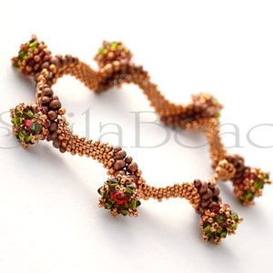 K&ouml;nnte beinhalten: Nahaufnahme von zwei Armb&auml;ndern aus Perlen. Die Armb&auml;nder sind kupferfarben mit Clustern aus gr&uuml;nen, roten und braunen Perlen. Die Armb&auml;nder befinden sich auf wei&szlig;em Hintergrund. Die Armb&auml;nder sind handgefertigt.