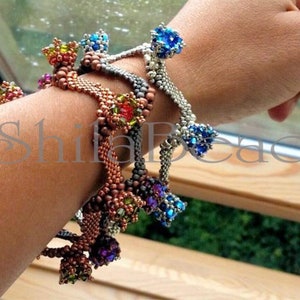 K&ouml;nnte beinhalten: Gezeigte Armb&auml;nder aus Perlen in verschiedenen Farben, darunter Kupfer, Silber und Dunkelgrau. Jedes Armband hat ein gewebtes Band und dekorative Cluster aus bunten Perlen. Das Bild enth&auml;lt den Text "ShifaBead".