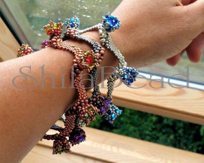 K&ouml;nnte beinhalten: Gezeigte Armb&auml;nder aus Perlen in verschiedenen Farben, darunter Kupfer, Silber und Dunkelgrau. Jedes Armband hat ein gewebtes Band und dekorative Cluster aus bunten Perlen. Das Bild enth&auml;lt den Text "ShifaBead".