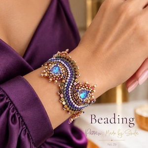 Puede incluir: Una pulsera de cuentas ancha e intrincada con dos grandes cabujones centrales de color azul iridiscente rodeados por filas de cuentas de semillas metálicas doradas, moradas y bronce. El texto "Beading Pattern Made by Shila No. 29" es visible abajo a la derecha.