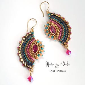 May include: A pair of handmade beaded earrings with a fan-like design. The earrings feature a gold hook, and are adorned with pink, teal, gold, and dark blue beads. A pink crystal dangles from the bottom. The text "Made by Shila" and "PDF Pattern" are visible.