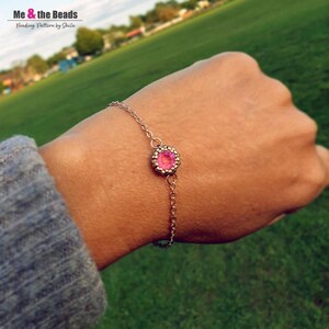 May include: A pink beaded bracelet with a silver chain and a pink gemstone charm.