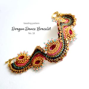 Op de afbeelding: Een kralenarmband met een gouden sluiting, met een ontwerp van roze, gouden, turquoise en bruine kralen. De armband is gelabeld "Dragon Dance Bracelet No. 18". Het ingewikkelde kralenwerk creëert een textuur, sierlijk uiterlijk.