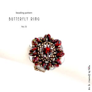 Puede incluir: Un anillo de cuentas con dise&ntilde;o de mariposa. El anillo presenta una gema roja central rodeada de cuentas rojas y doradas m&aacute;s peque&ntilde;as. El texto "BUTTERFLY RING" y "No 25" son visibles. El anillo est&aacute; sobre un fondo blanco.