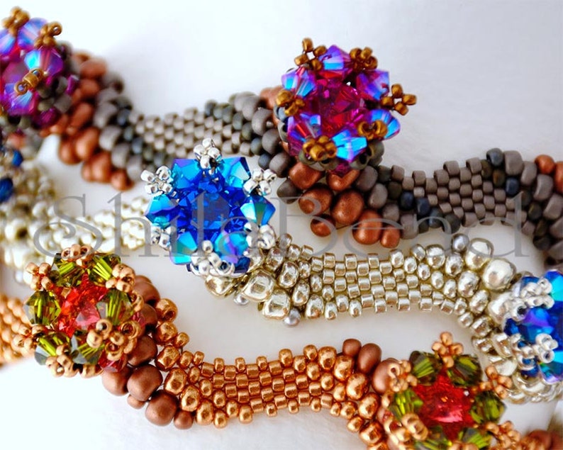 K&ouml;nnte beinhalten: Nahaufnahme von Perlenschmuck mit aufwendigen Designs. Die St&uuml;cke zeigen eine Vielzahl von Farben, darunter Blau, Rot, Gr&uuml;n und Gold, mit Fokus auf die detaillierte Perlenarbeit und funkelnde Akzente. Der Schmuck scheint handgefertigt zu sein.