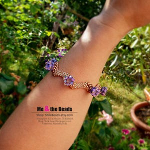 K&ouml;nnte beinhalten: Ein Armband mit lila und goldenen Akzenten. Das Armband hat lila Perlen und gr&ouml;&szlig;ere, facettierte lila Steine. Das Band besteht aus kleinen goldenen Perlen. Der Text "Me & the Beads" ist im Bild zu sehen.