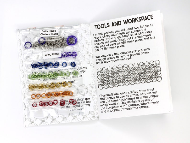 A photo of the diy kit opened to the first page. On the inside of the cover you can see the materials of the kit wraped in plastic bags. The first page features black text on a white page and describes the tools needed for the project, two pairs of pliers, and a brief history of chainmail.