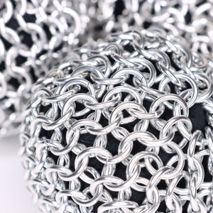 A very close up example of a finished silver chainmail ball against a white background.