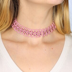 A pink oversized tattoo choker made with pink rubber rings connected by shiny pink metal rings in a chainmail pattern.