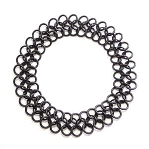 An oversized chainmail tattoo choker laying in a flat circle on a white table. The full choker is visible, showing the seamless design without a clasp.