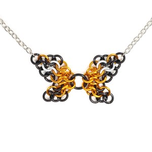 An example of a finished chainmail butterfly pendant in an orange monarch pattern against a white background.
