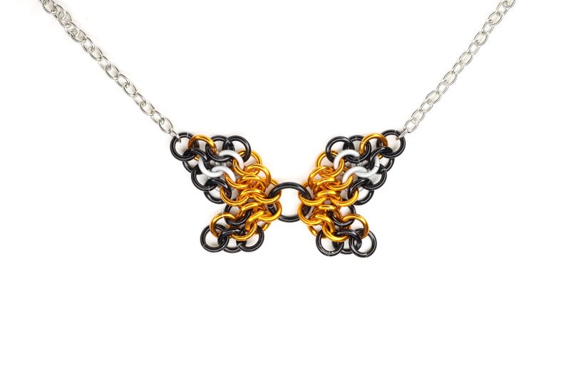 An example of a finished chainmail butterfly pendant in an orange monarch pattern against a white background.