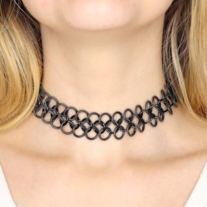 An oversized black chainmail necklace in the style of a tattoo choker rests in the middle of a models neck. The stretchy necklace is made from two rows of large rubber rings, connected with a center row of metal rings. Handmade in your choice of size and a rainbow of colors.