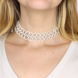 A white oversized tattoo choker made with white rubber rings connected by matte white metal rings in a chainmail pattern.