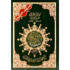 May include: A hardcover book with a dark green cover and gold and white decorative accents. The cover features Arabic script and a central starburst design. The title "مصْحَف التَّجْوِيد" is visible.