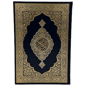 May include: A hardcover book with a dark blue cover and intricate gold filigree designs. The cover features a central medallion with Arabic calligraphy and ornate borders. The book's edges are also gold, creating a luxurious appearance.