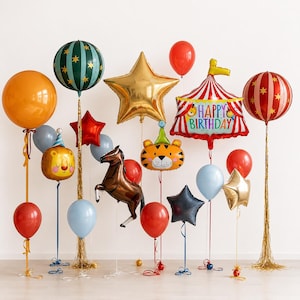 May include: A collection of circus-themed balloons including a large orange sphere, a green star-patterned sphere, a gold star, a red and white striped tent balloon with the text Happy Birthday, a brown horse, a tiger face, and various solid color balloons.