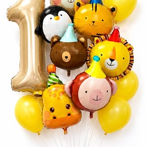 May include: A balloon bouquet featuring a large gold number one foil balloon, several yellow latex balloons, and various animal-shaped foil balloons including a bear, penguin, tiger, lion, monkey, and giraffe, all wearing colorful party hats.