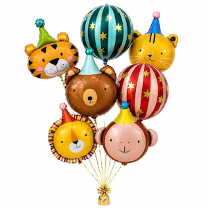 May include: A bouquet of foil balloons in the shape of animal faces, including a tiger, bear, lion, and monkey, each wearing a party hat. Additional round balloons feature stripes and stars. The balloons are tied together with gold ribbon.