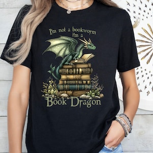 May include: Black t-shirt with a green dragon holding a stack of books. The text on the shirt reads "I'm not a bookworm I'm a Book Dragon".