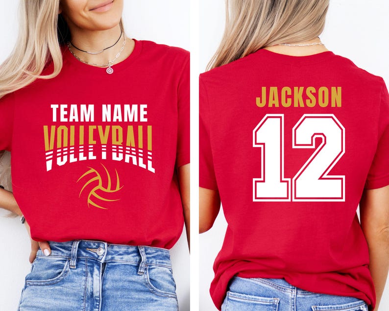 May include: Red volleyball t-shirt with the words "TEAM NAME VOLLEYBALL" in white and gold. A volleyball graphic is below the text. The back of the shirt has the name "JACKSON" and the number "12" in white with a gold outline.