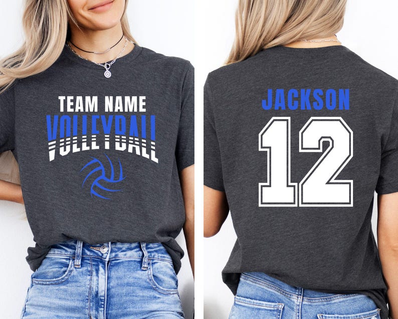 May include: Dark gray t-shirt with the words "TEAM NAME VOLLEYBALL FULL BALL" in white and blue, along with a volleyball graphic. The back of the shirt displays "JACKSON 12" in blue and white.