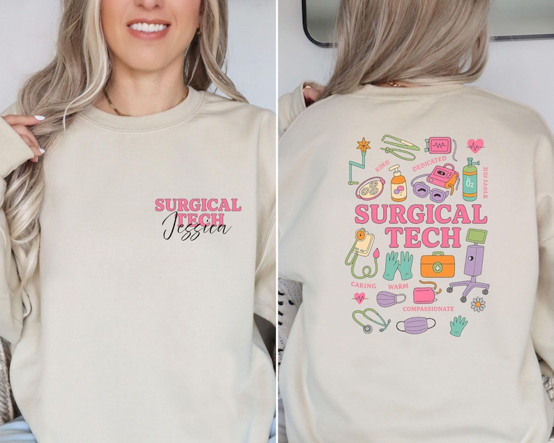 May include: Beige sweatshirt with the text "SURGICAL TECH Jessica" in pink and black on the front. The back features a colorful graphic with medical equipment and the words "SURGICAL TECH", and the words "Caring, Warm, Compassionate".