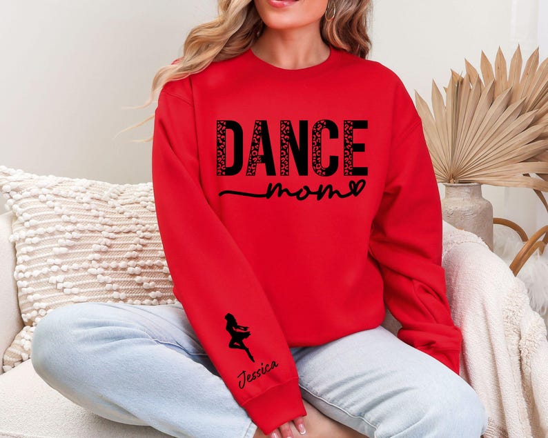 May include: Red sweatshirt with the text "Dance Mom" in black with a heart and a small dancer silhouette on the sleeve. The text is in a sparkly font.