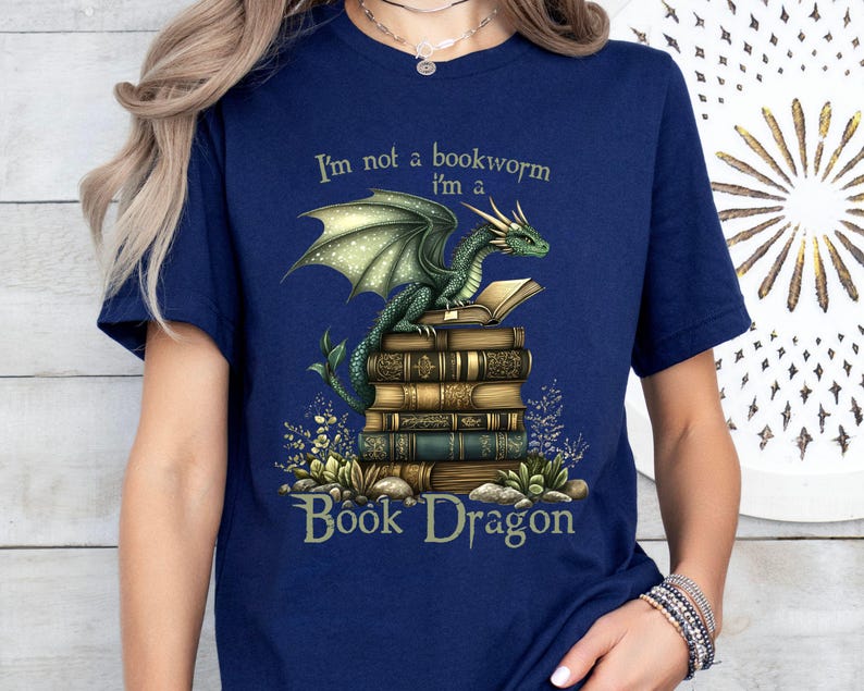 May include: A navy blue t-shirt with a green dragon sitting on a stack of books. The text "I'm not a bookworm I'm a Book Dragon" is printed on the shirt.