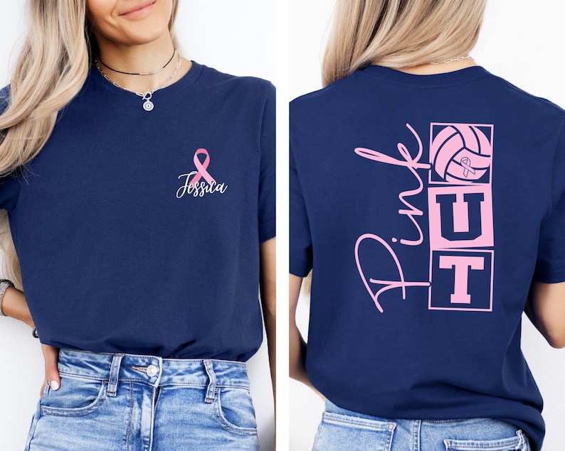 May include: Navy blue t-shirt with a pink ribbon and the name "Jessica" on the front. The back of the shirt features the words "Pink UT" with a volleyball graphic, also in pink. The shirt is a short-sleeved crew neck.