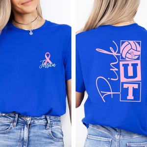 May include: Royal blue t-shirt with a pink ribbon and the name "Jessica" printed on the front. The back of the shirt features the words "Pink UT" with a volleyball graphic in pink. A casual tee for sports fans.